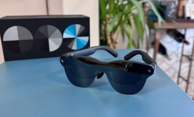 Smart glasses on a blue surface with a box and plant in the background.