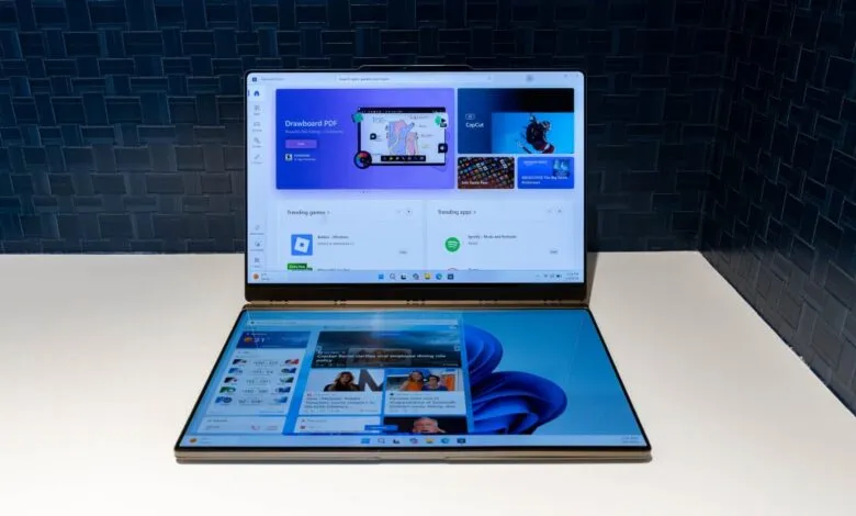 Dual-screen laptop displaying Microsoft Store and news articles.