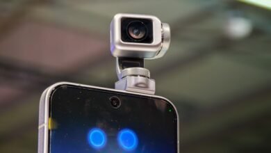 Smartphone with a small, silver robotic camera attached to the top.