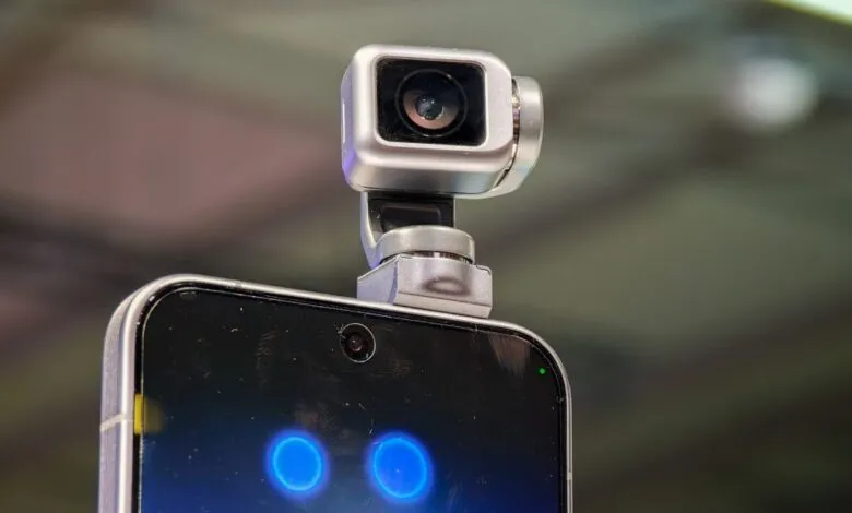 Smartphone with a small, silver robotic camera attached to the top.