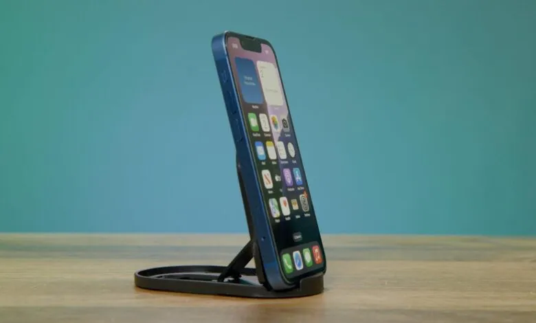 Blue iPhone 13 mini on a black stand, angled view.