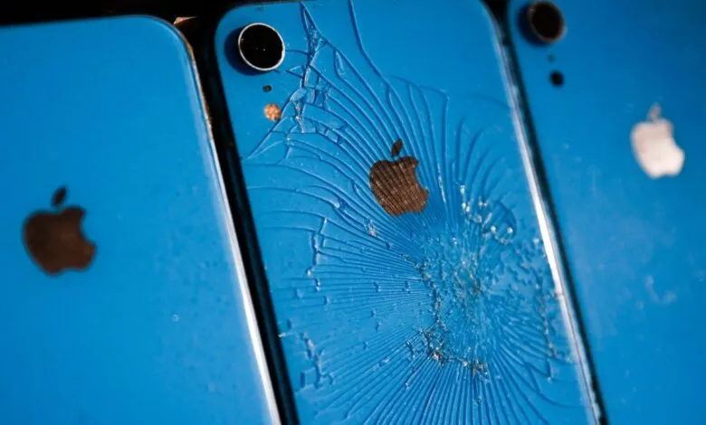 Close-up of a cracked blue iPhone with shattered back glass.