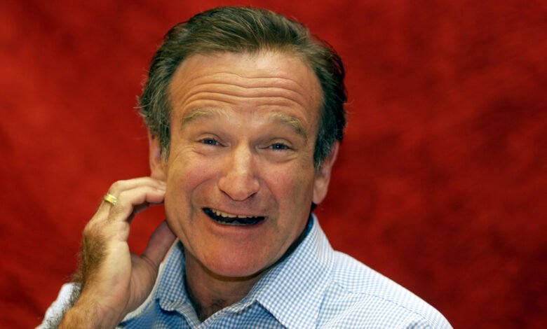 Close-up of Robin Williams smiling with hand near his face.