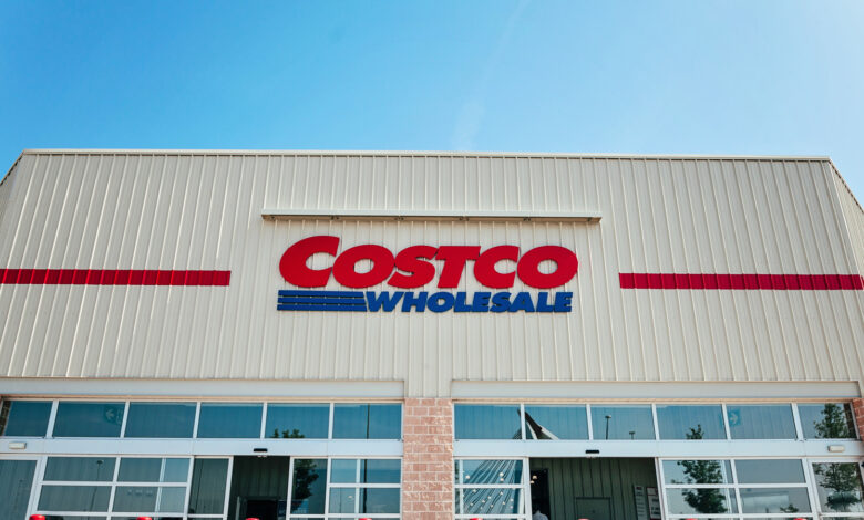 Exterior view of a Costco Wholesale store under a clear blue sky.