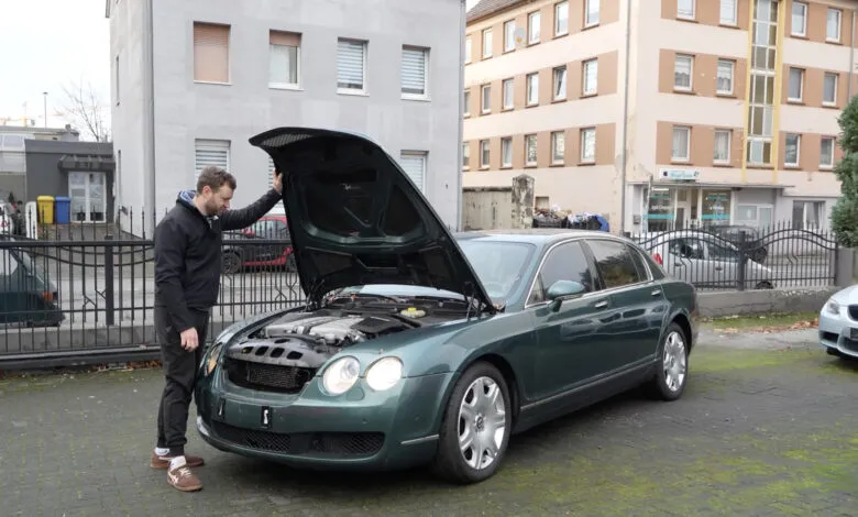 Man inspecting the engine of a green Bentley with the hood open.