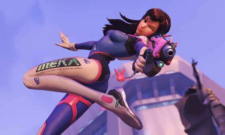 D.Va from Overwatch winks, holding a pink gun, mid-air with a building in the background.