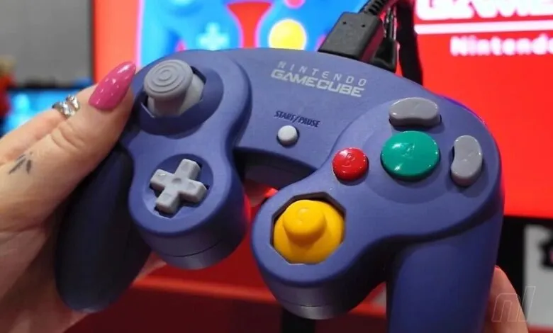 Close-up of a purple Nintendo GameCube controller being held.