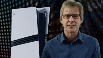 Man stands next to a PlayStation 5 console against a pixelated background.