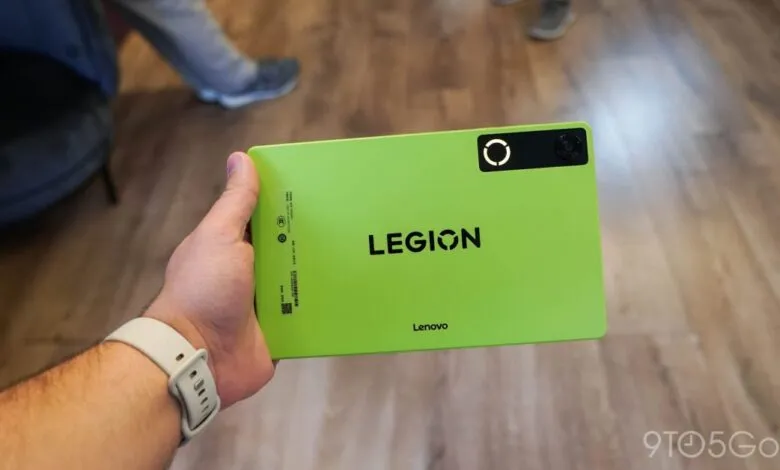 Close-up of a green Lenovo Legion Tab held by a person wearing a smartwatch.