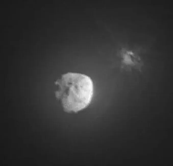 Monochrome image of asteroid Dimorphos after DART impact, showing ejecta.