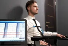 Man undergoing lie detector test with visible pulse diagrams on computer.