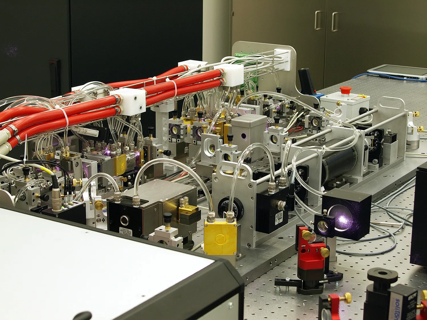 Complex laser system with red tubes, silver components, and optical elements.