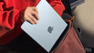 Person placing a silver MacBook Air into a maroon backpack.