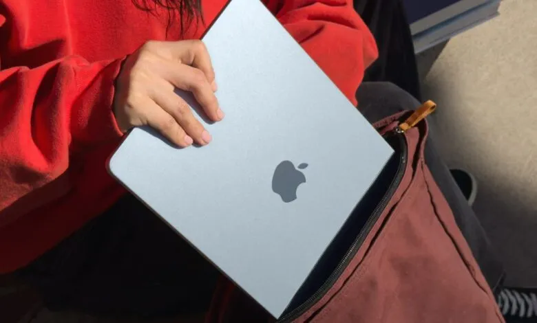 Person placing a silver MacBook Air into a maroon backpack.