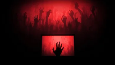 Silhouetted hands reach from a red screen, evoking a horror movie scene.