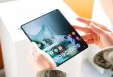 Person holding a Motorola Razr foldable phone displaying the home screen.