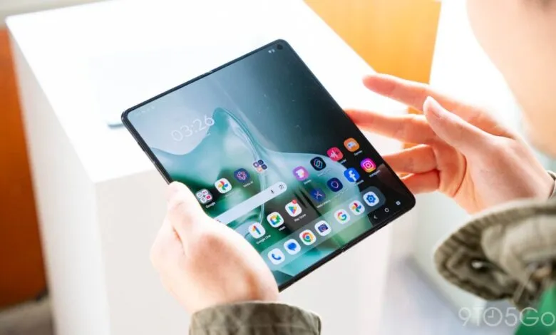 Person holding a Motorola Razr foldable phone displaying the home screen.