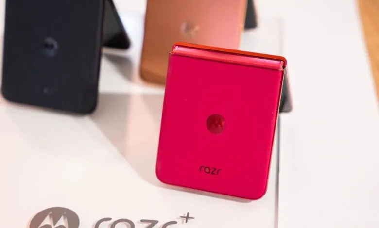 Closed red Motorola Razr+ foldable phone on display stand.