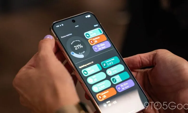 Close-up of hands holding phone displaying Fitbit app with fitness metrics.
