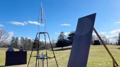 Outdoor rocket launch setup with metal rocket, corrugated panels, and blue sky.