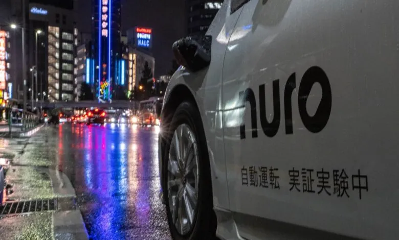 Nuro autonomous vehicle on a wet city street at night.