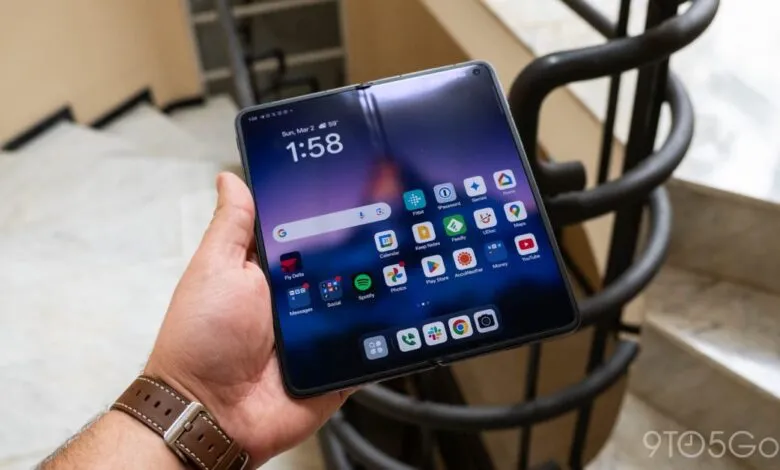 Hand holding unfolded Oppo Find N2 showing app icons on the screen.