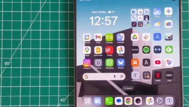Smartphone screen displaying app icons and widgets on a green cutting mat.