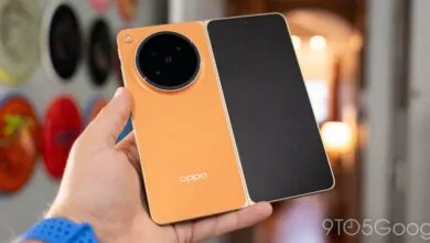 Hand holding open orange Oppo Find N foldable phone with large camera module.