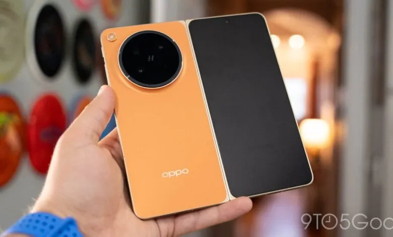Hand holding open orange Oppo Find N foldable phone with large camera module.