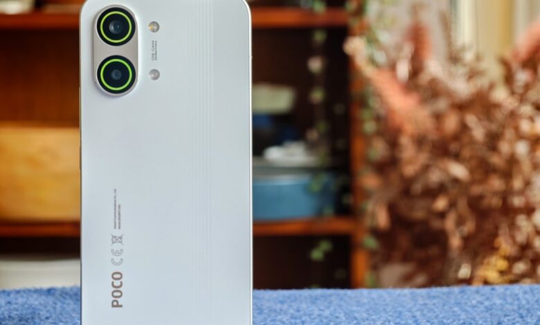 Close-up of a white POCO phone showing the camera array and branding.