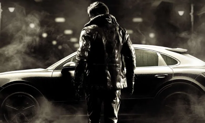Man in leather jacket stands by a sleek Porsche car in the fog.