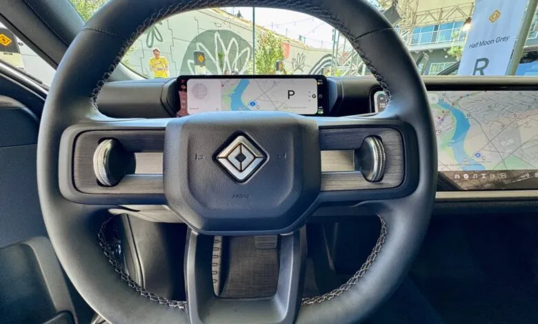Close-up of Rivian steering wheel with integrated screens and textured controls.