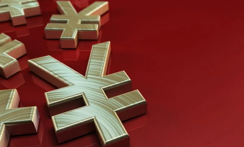 Several gold Yen symbols scattered on a shiny red surface.