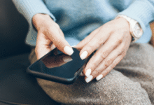 Hands with white nails hold a smartphone, suggesting tech interaction.