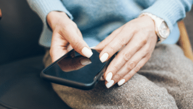 Hands with white nails hold a smartphone, suggesting tech interaction.