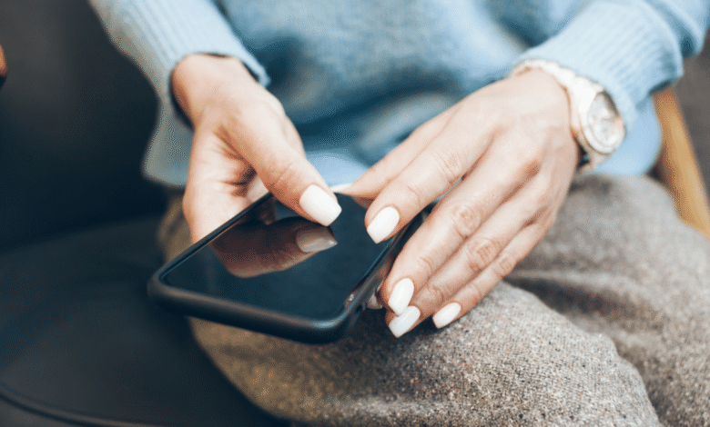 Hands with white nails hold a smartphone, suggesting tech interaction.