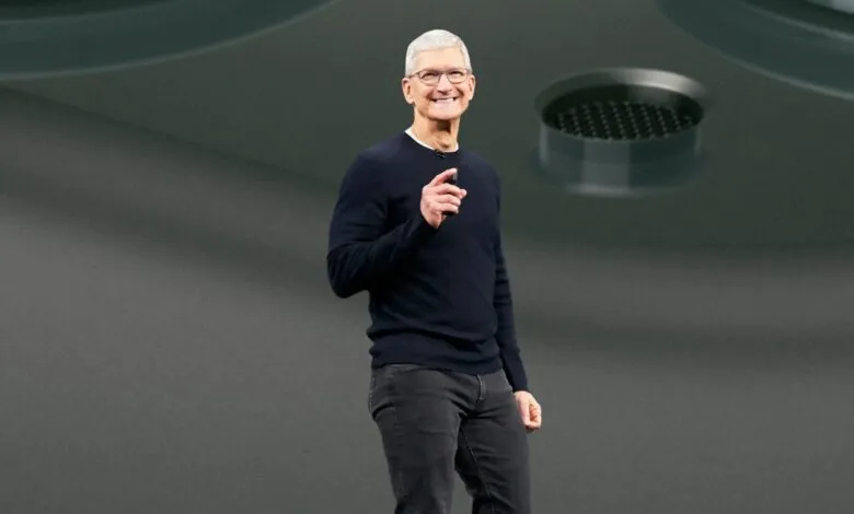 Tim Cook, Apple CEO, smiles and gestures on stage during an Apple event.