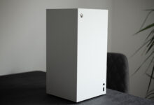 White Xbox Series S console standing vertically on a dark textured surface.