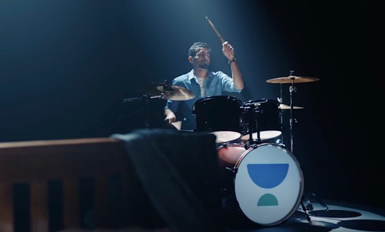 Drummer playing set with Unacademy logo in spotlight.
