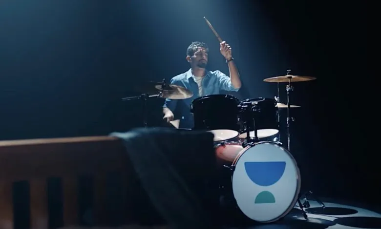Drummer playing set with Unacademy logo in spotlight.