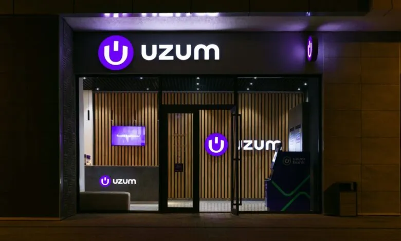 Exterior view of an Uzum Bank branch at night, showcasing its modern design.
