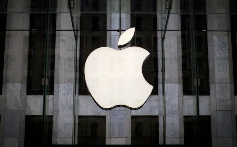 Apple logo hangs in front of a building with glass and marble.
