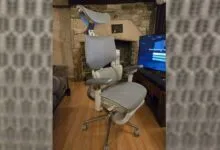 Ergonomic office chair with headrest and adjustable arms in a living room setting.