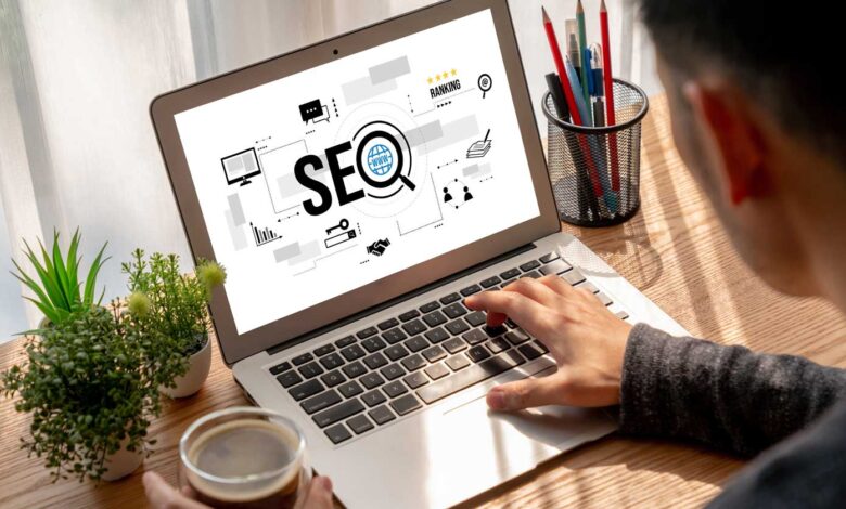 Person types on laptop displaying SEO graphic, coffee and plants nearby.