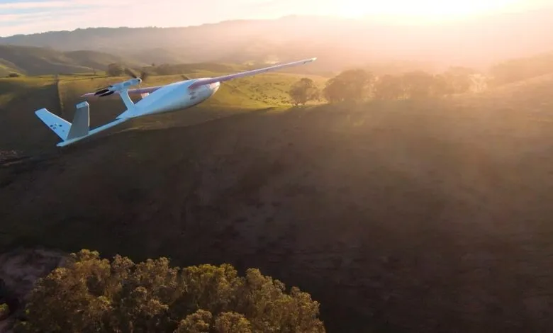 Zipline drone flying over hilly landscape at sunset, delivering medical supplies.