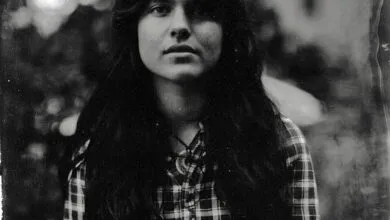 Black and white portrait of a young woman with long hair wearing a plaid shirt.