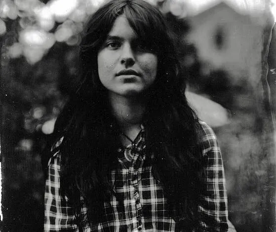 Black and white portrait of a young woman with long hair wearing a plaid shirt.