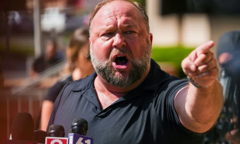Alex Jones passionately speaks at a press conference, pointing forward.