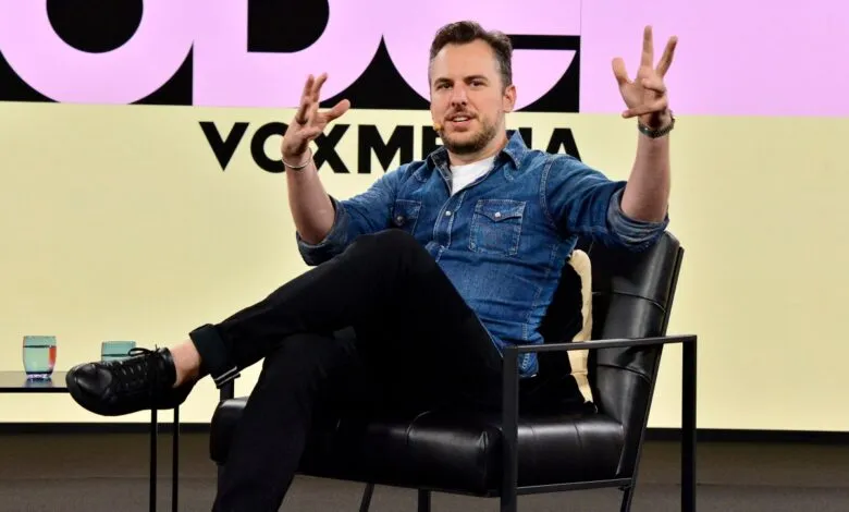 Man in denim shirt gestures while seated on stage at Vox Media event.