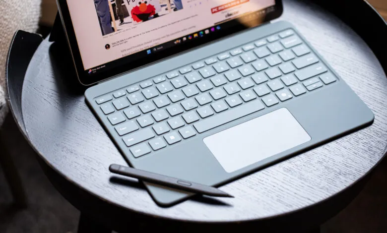 Surface Pro tablet with keyboard and pen on a dark wooden table.